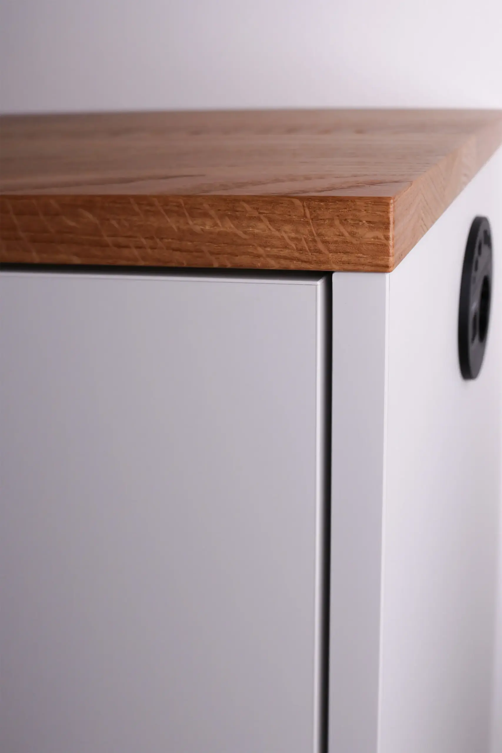 Nahaufnahme der Holzkante und weißen Front eines maßgefertigten Sideboards