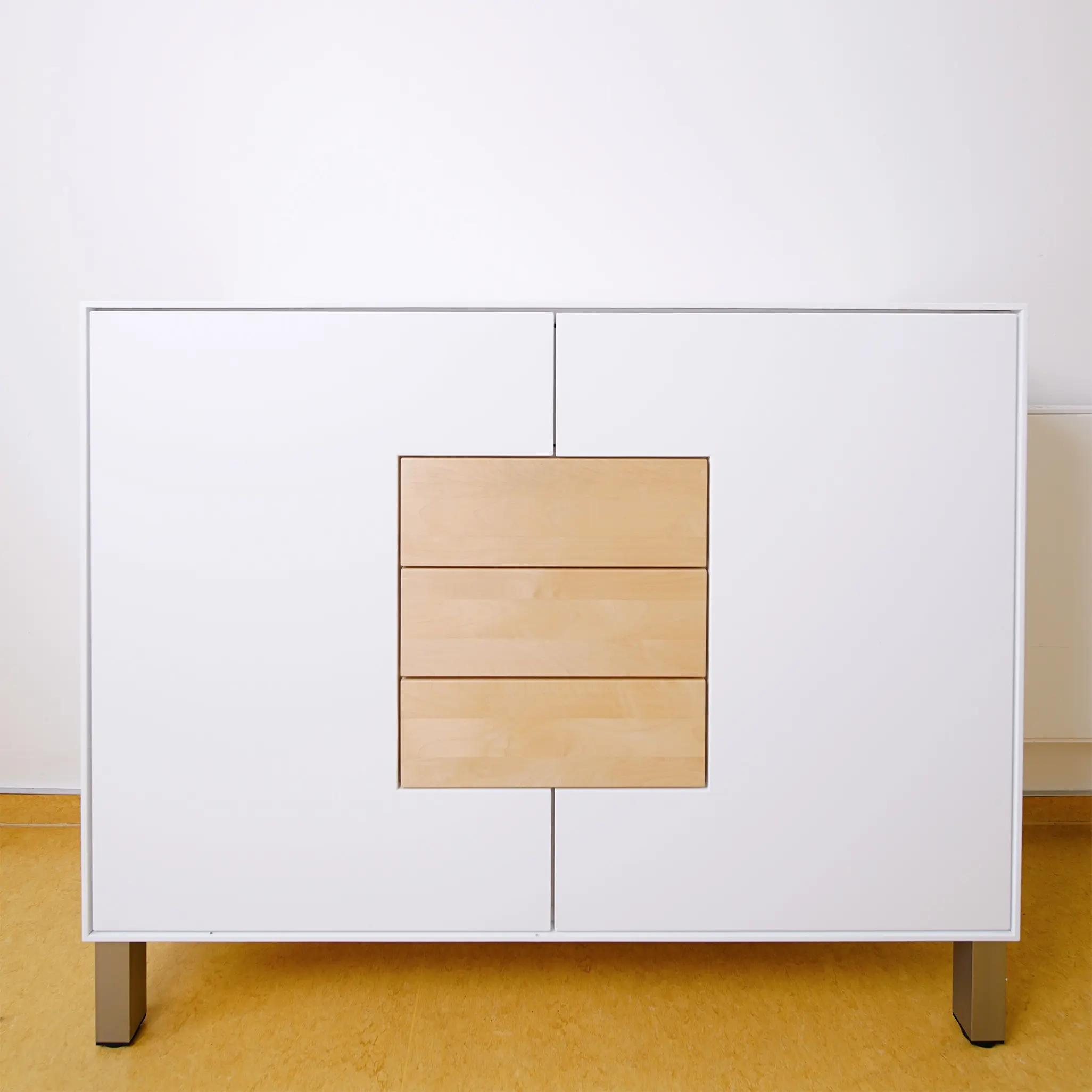 Modernes weißes Highboard mit zwei großen Schranktüren und drei mittig angeordneten Holzschubladen