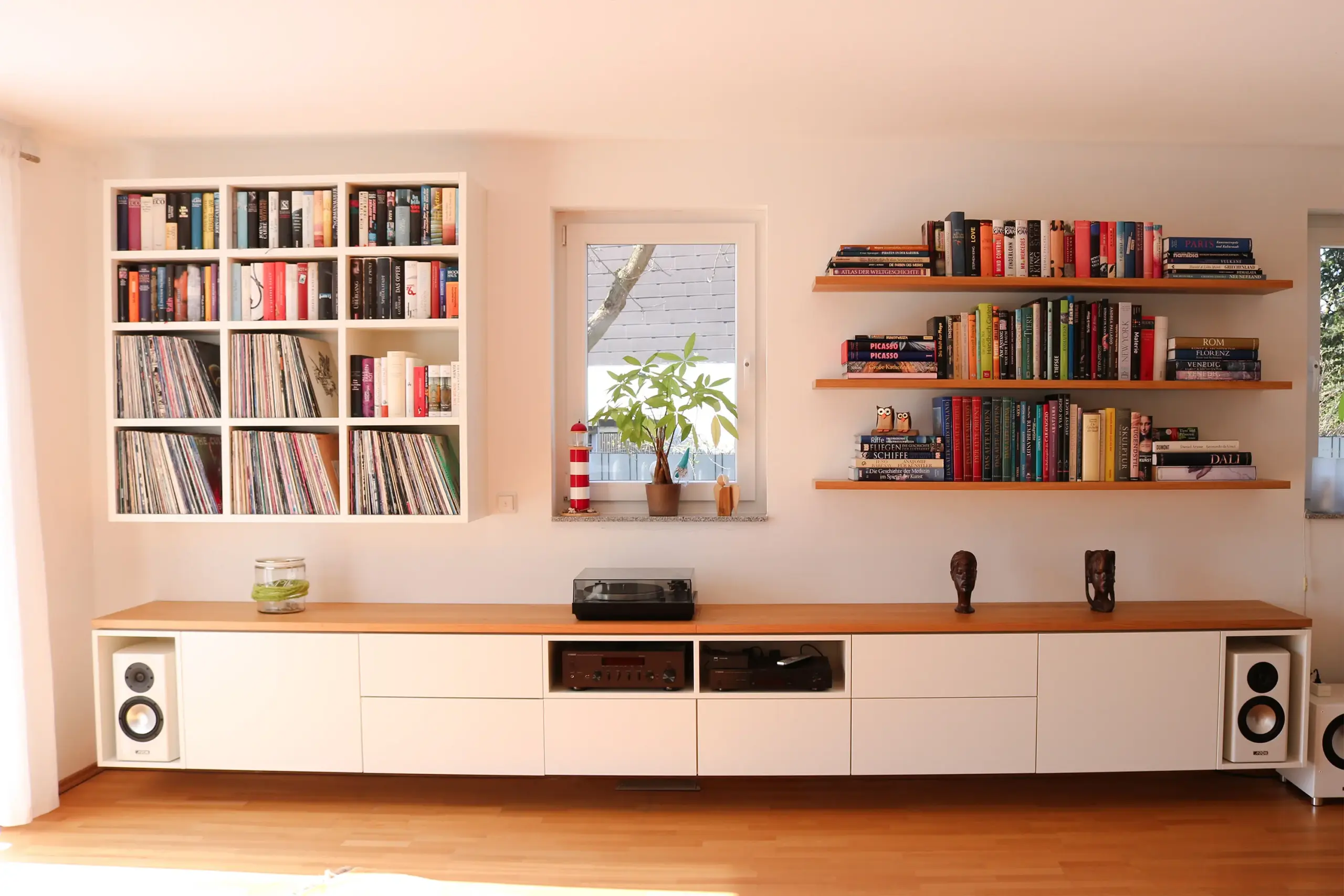 Großes maßgefertigtes Medien-Sideboard mit Holzabdeckung, integrierten Lautsprechern, Hi-Fi-Technik sowie Bücherregalen im Wohnraum