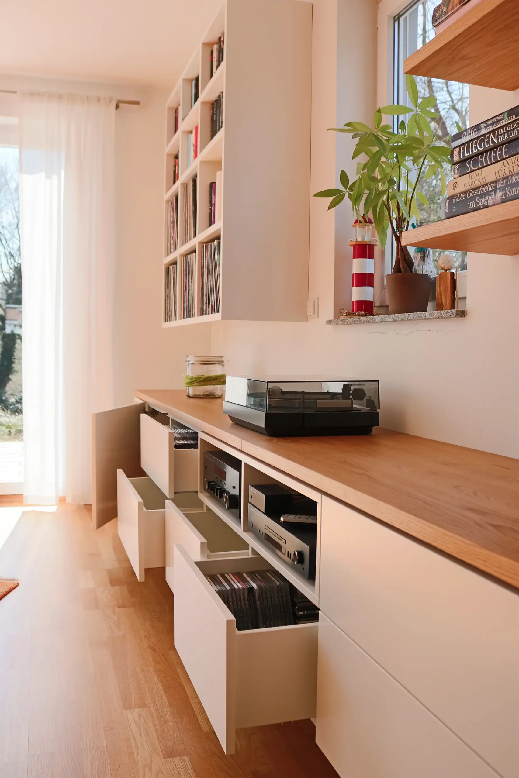Maßgefertigtes Medien-Sideboard mit geöffnete Schubladen, integrierter Hi-Fi-Technik und Holzabdeckung im Wohnbereich