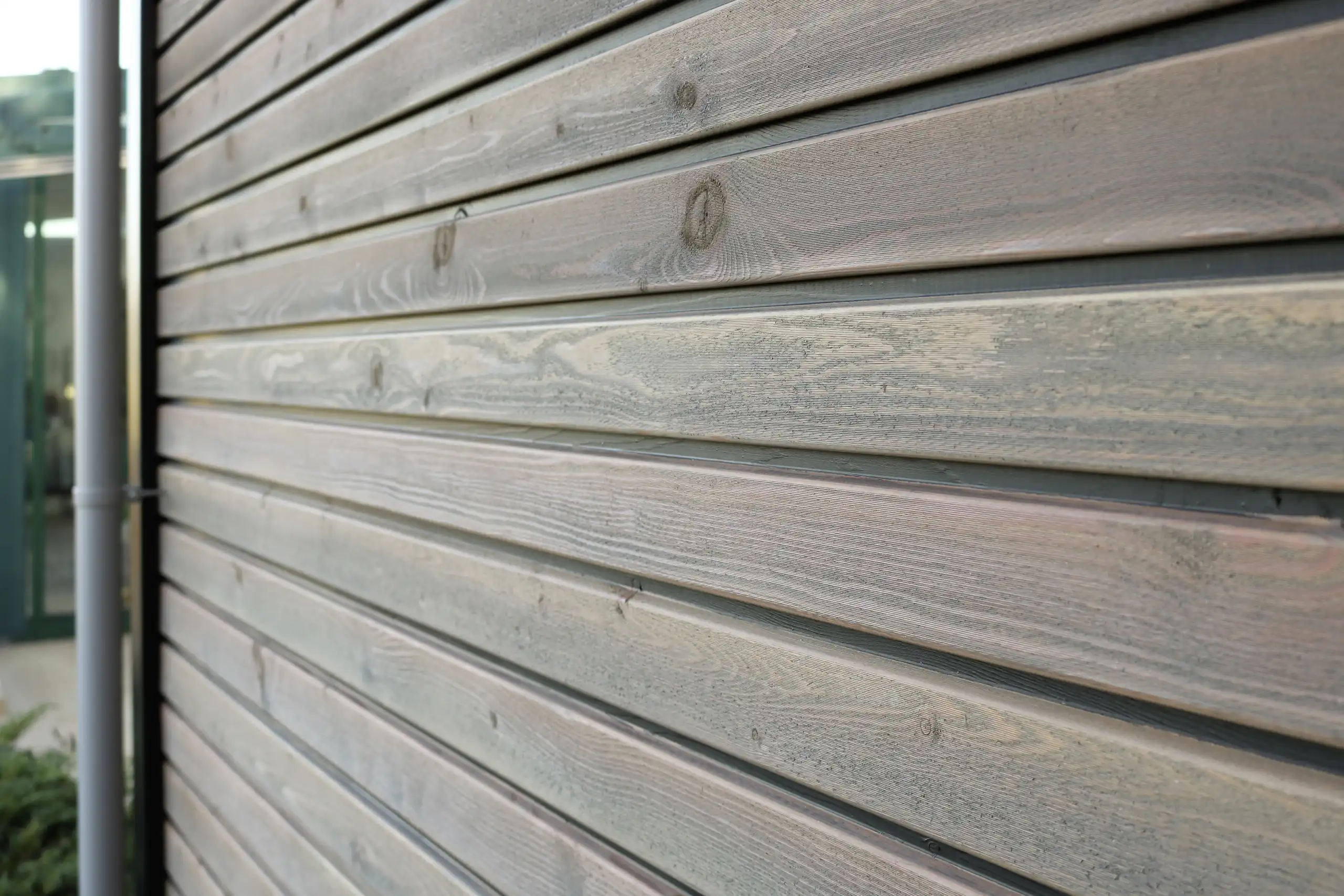 Nahaufnahme der horizontalen Holzverschalung einer Gartenhütte in grau verwitterter Optik