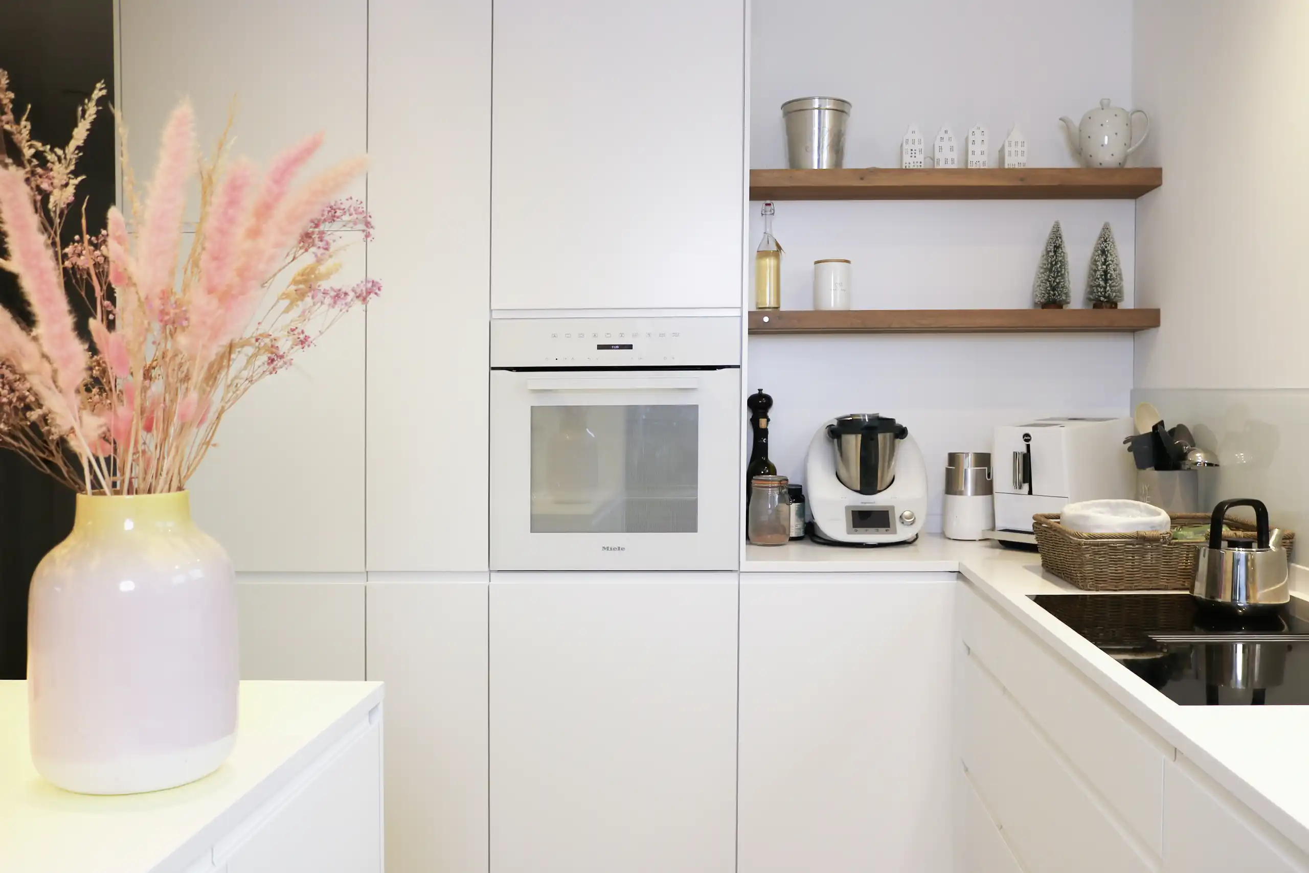 Puristische weiße Einbauküche mit integriertem Backofen, offenen Holzregalen und Kochfeld