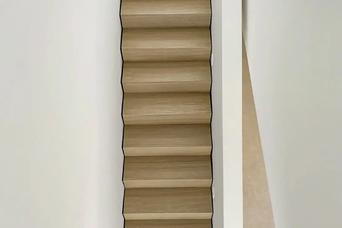 Schmale Holztreppe mit durchgehender Schattenfuge zwischen den hellen Eichenstufen und den weißen Wänden