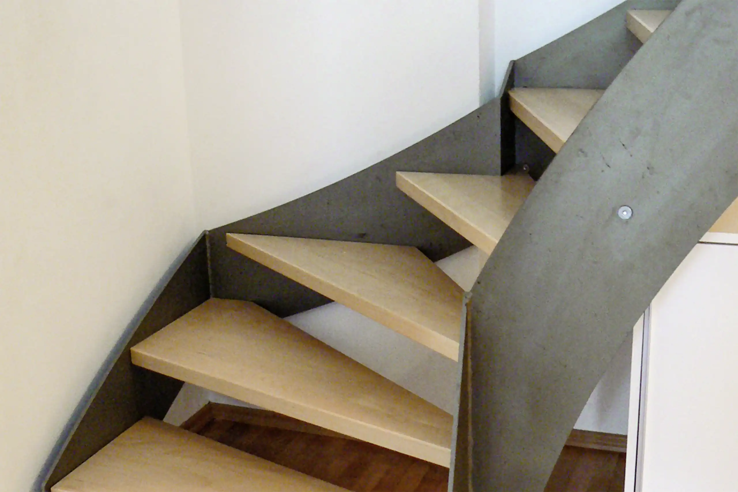 Moderne Wangentreppe mit hellen Holzstufen und dunkelgrauen seitlichen Stahlwangen