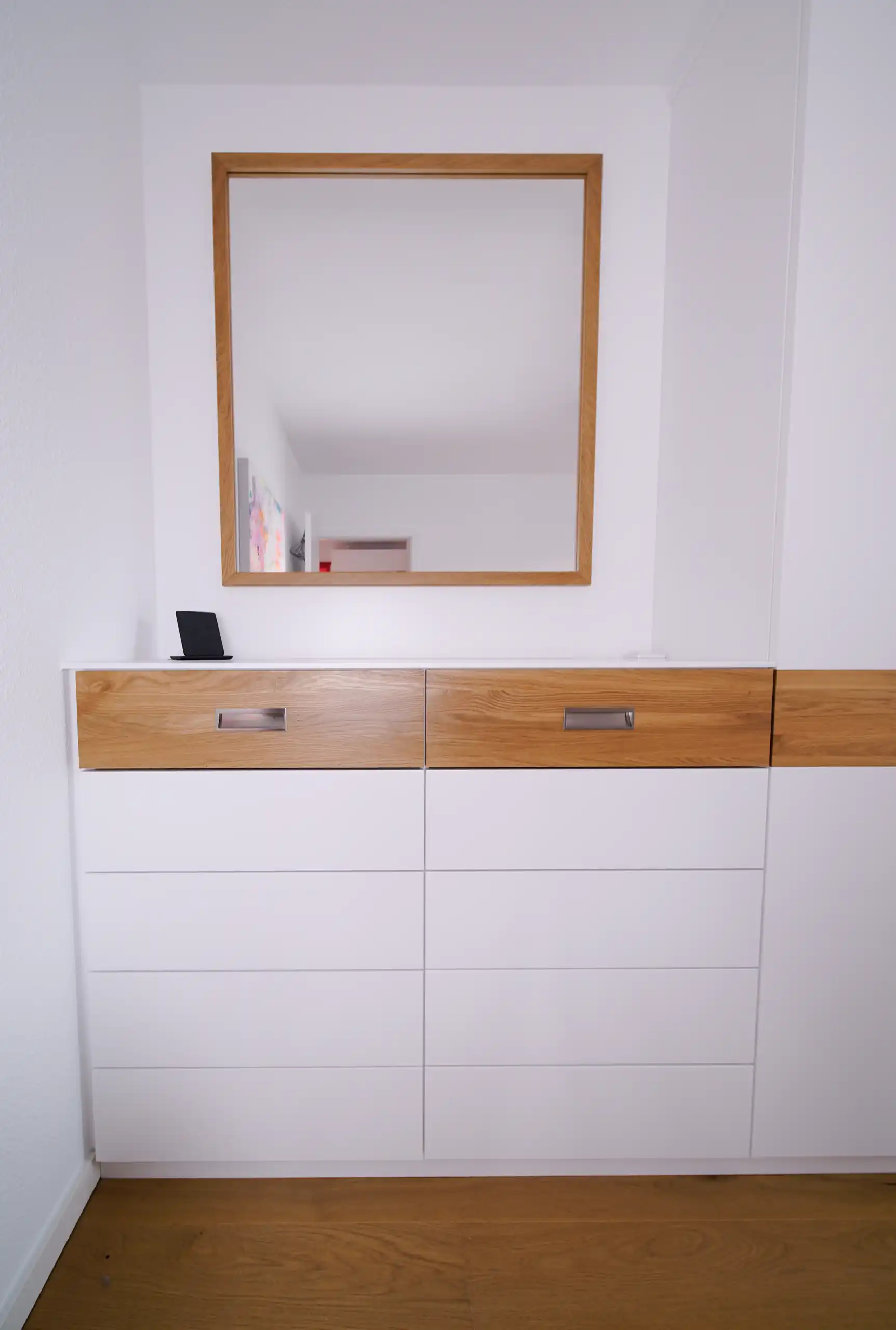 Maßgefertigte weiße Kommode mit Eichenholzschubladen und großem Wandspiegel im Schlafzimmer