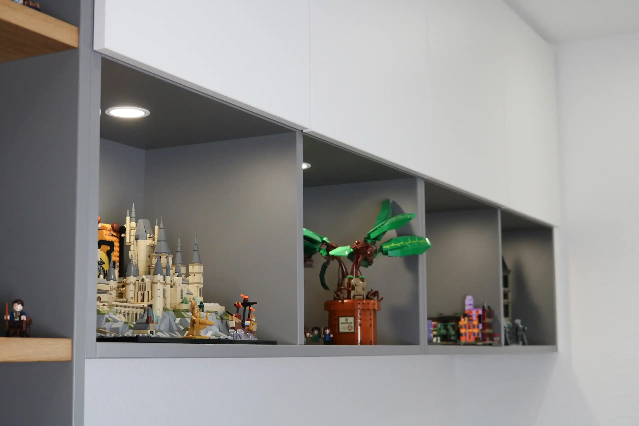 Beleuchtete Einbaunischen mit LEGO-Modellen und weißen Oberschränken in einem Kinderzimmer