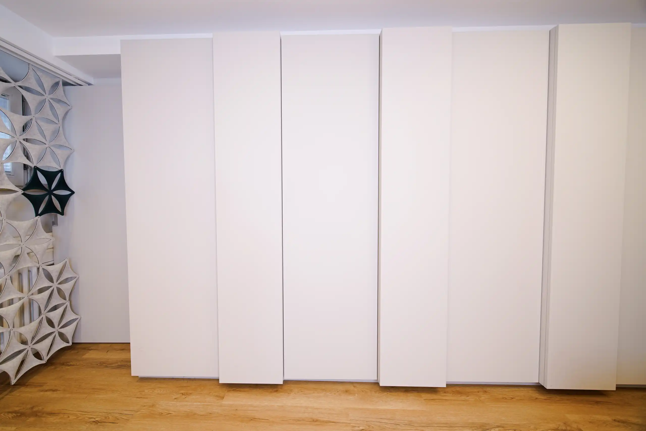 Individuell angepasster weißer Einbauschrank mit versetzten Fronten in einem hellen Wohnbereich