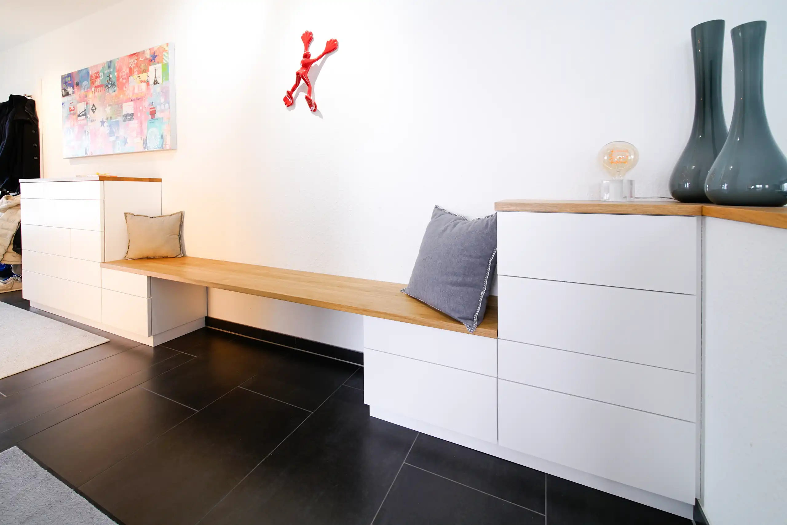 Individuelle Garderobenlösung mit weißen Kommoden, durchgehender Eichenholz-Sitzbank und zusätzlichem Stauraum