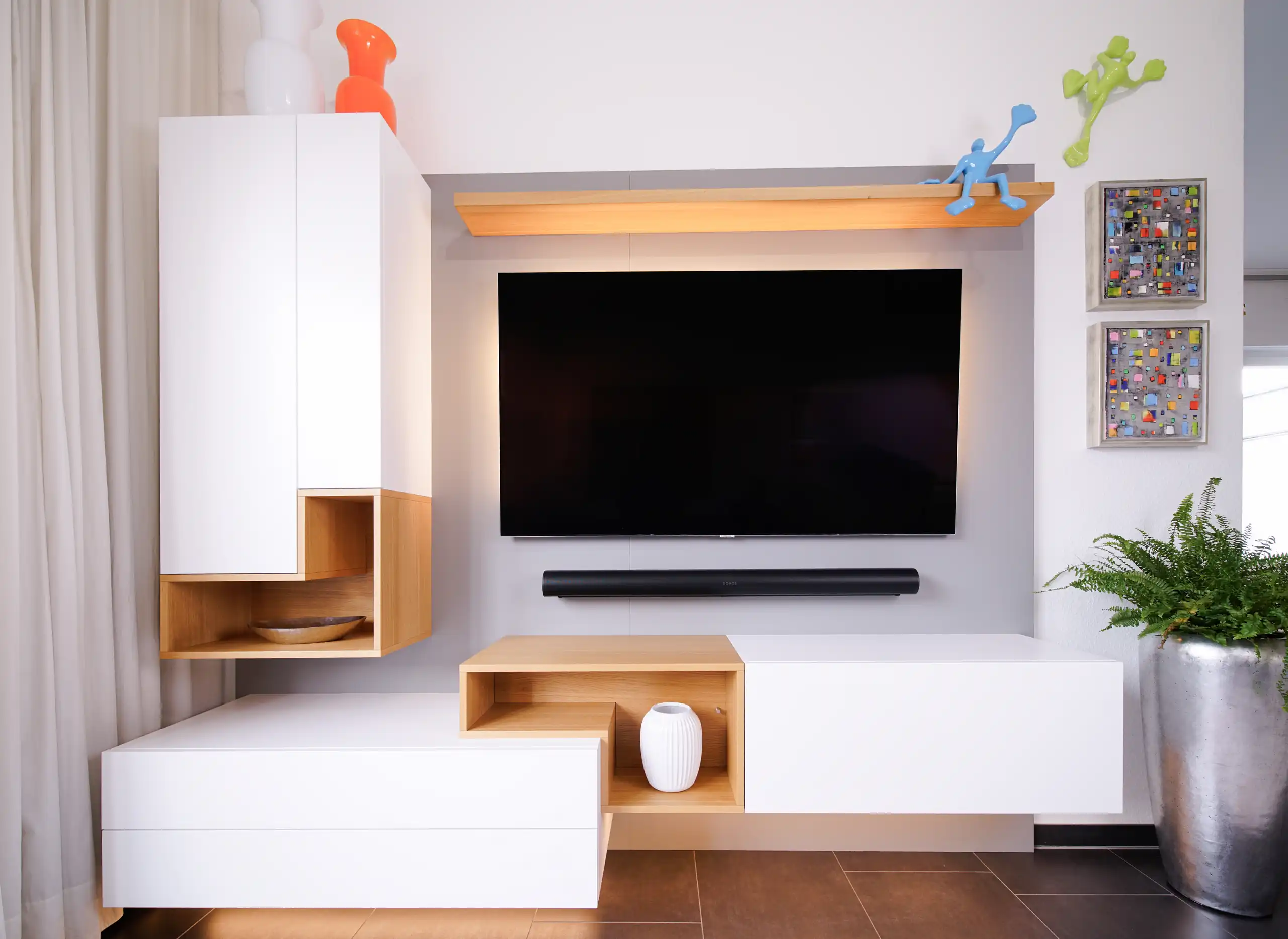 Maßgefertigte Medienwand mit weißem Stauraum, offenen Holzregalfächern, wandmontiertem Fernseher und Soundbar