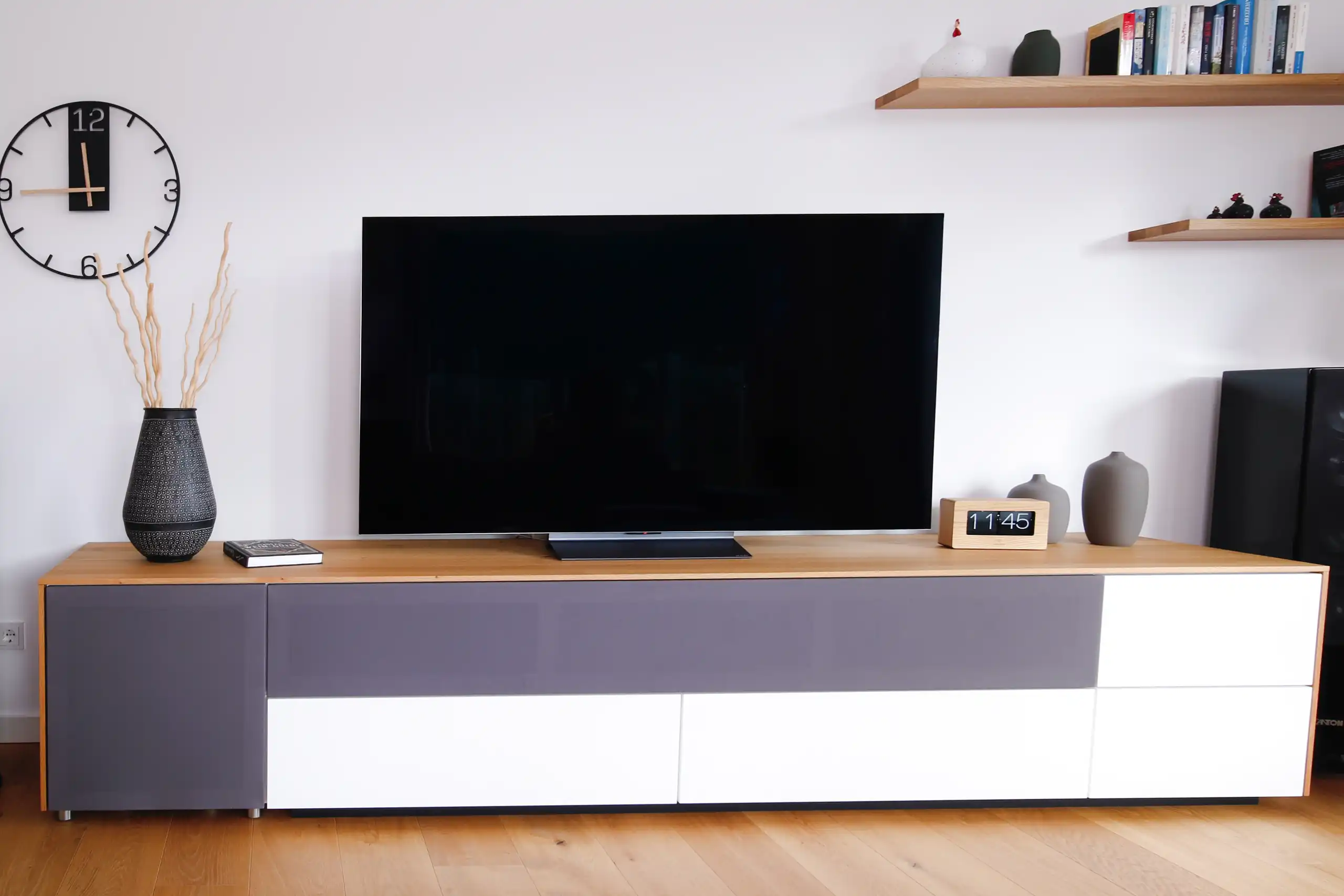 Modernes TV-Sideboard mit Holzplatte, grauen und weißen Fronten sowie großem Fernseher im Wohnbereich