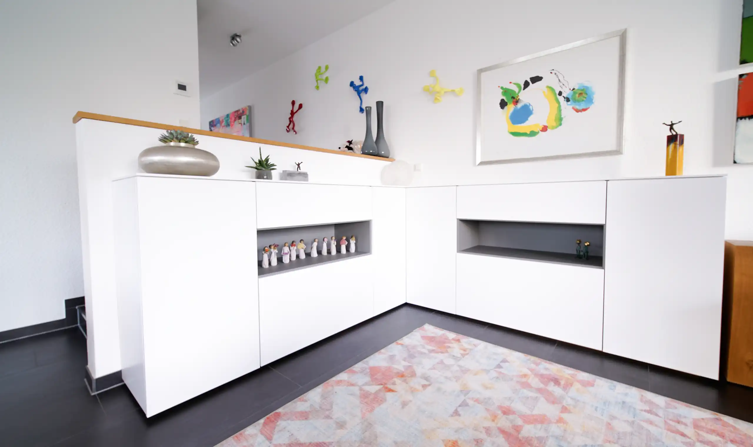 Maßgefertigtes weißes Eck-Sideboard mit offenen grauen Regalfächern in einem modernen Wohnbereich
