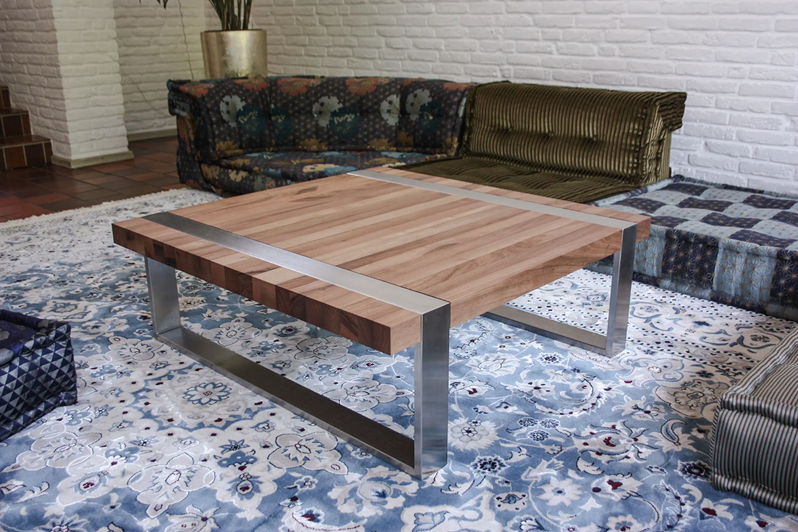 Handgefertigter Couchtisch aus Massivholz mit Edelstahlgestell in einem Wohnbereich auf gemustertem Teppich